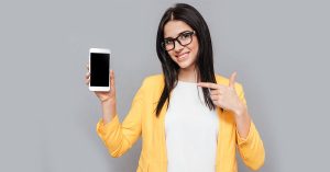 Egy nő mobiltelefonnal az egyik kezében, míg a másikkal rá mutat